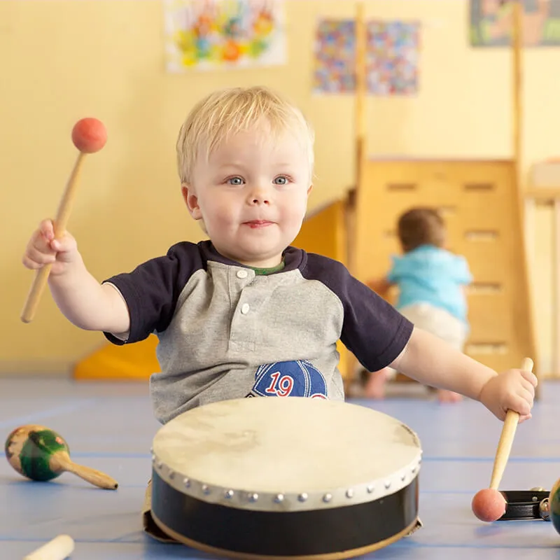 Young child playing a drum with mallets