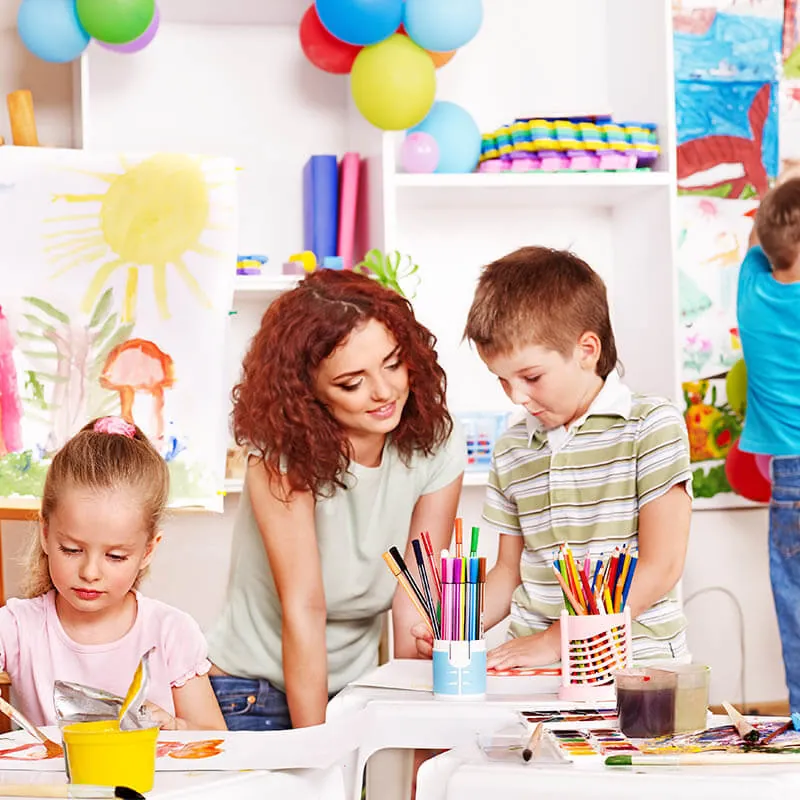 Teacher helping children with drawing and crafts